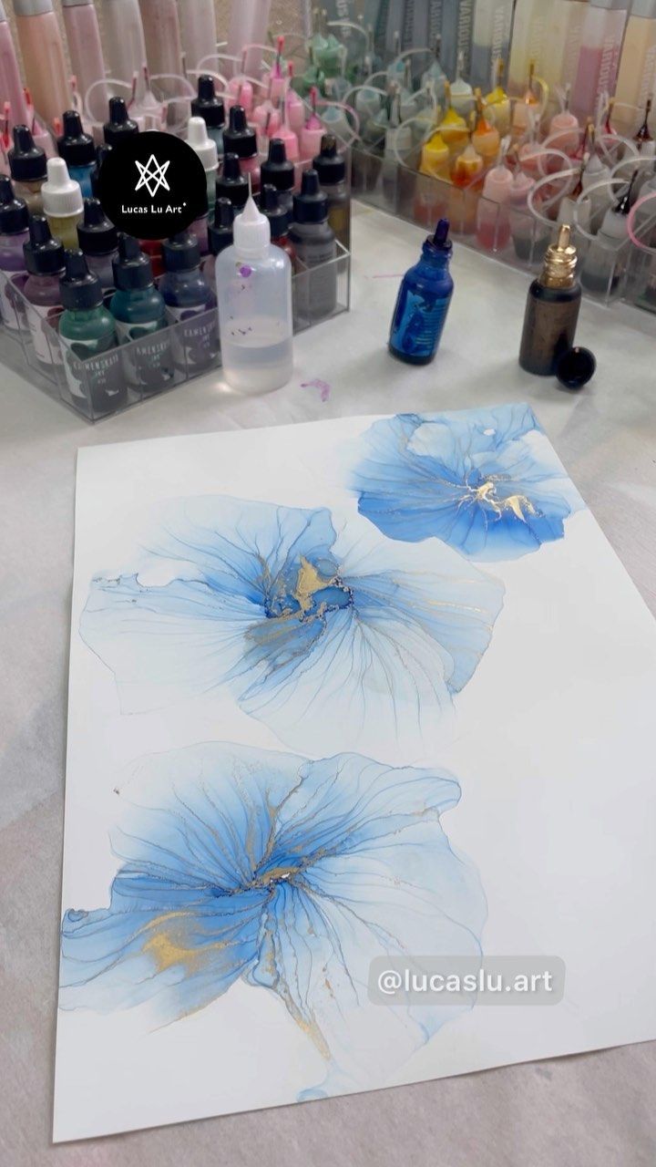 blue flowers on white paper next to bottles of nail polish and other art supplies in the background