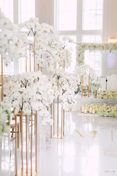 a room filled with lots of white flowers and gold vases next to each other