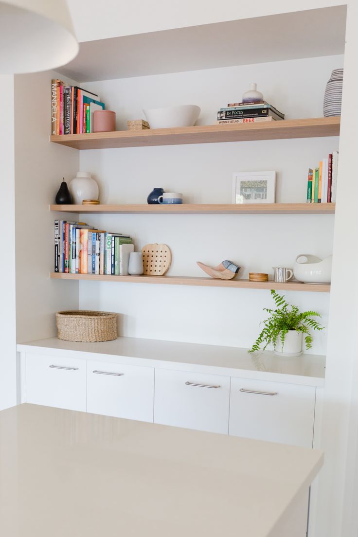 the shelves are filled with books and other things on top of the countertop in this kitchen