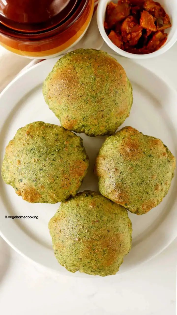 three green muffins on a white plate next to bowls of sauce and condiments