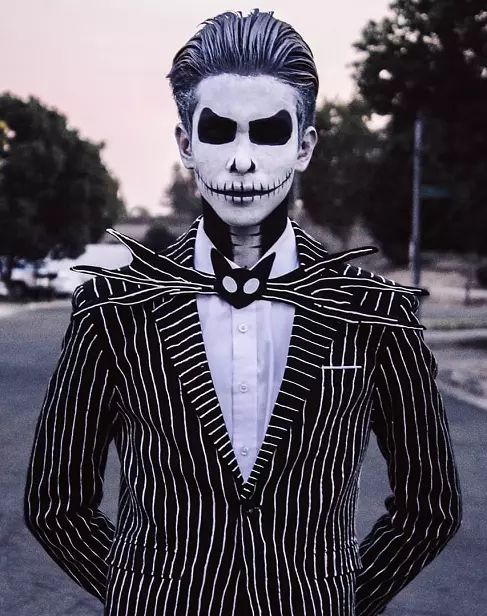 a man dressed up in a skeleton suit and bow tie with his hands on his hips