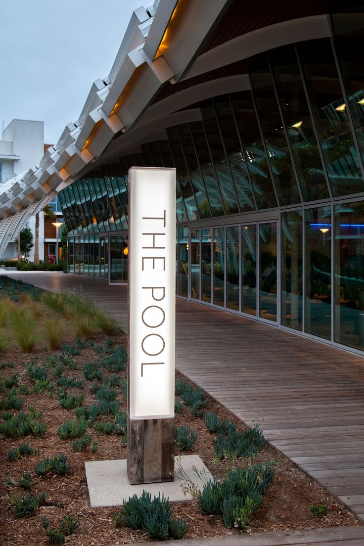 a sign that reads the loop in front of a building with glass windows and plants