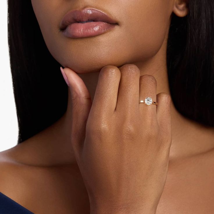 a woman wearing a diamond ring with her right hand on her left shoulder, looking at the camera