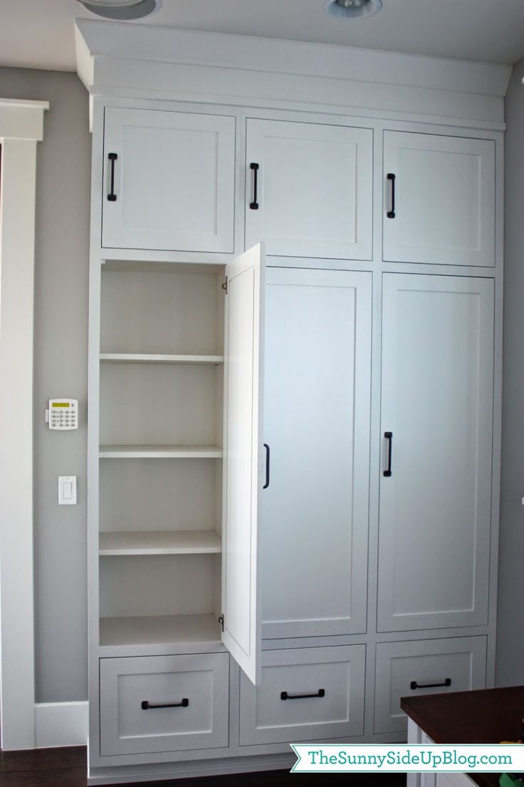 an empty room with white cupboards and shelves on the wall, in front of a window