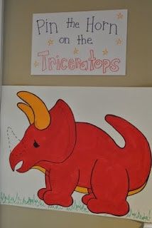 a drawing of a red dinosaur on the wall next to a sign that says pin the horn on the tricletops