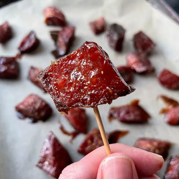 a hand holding a piece of food on a stick