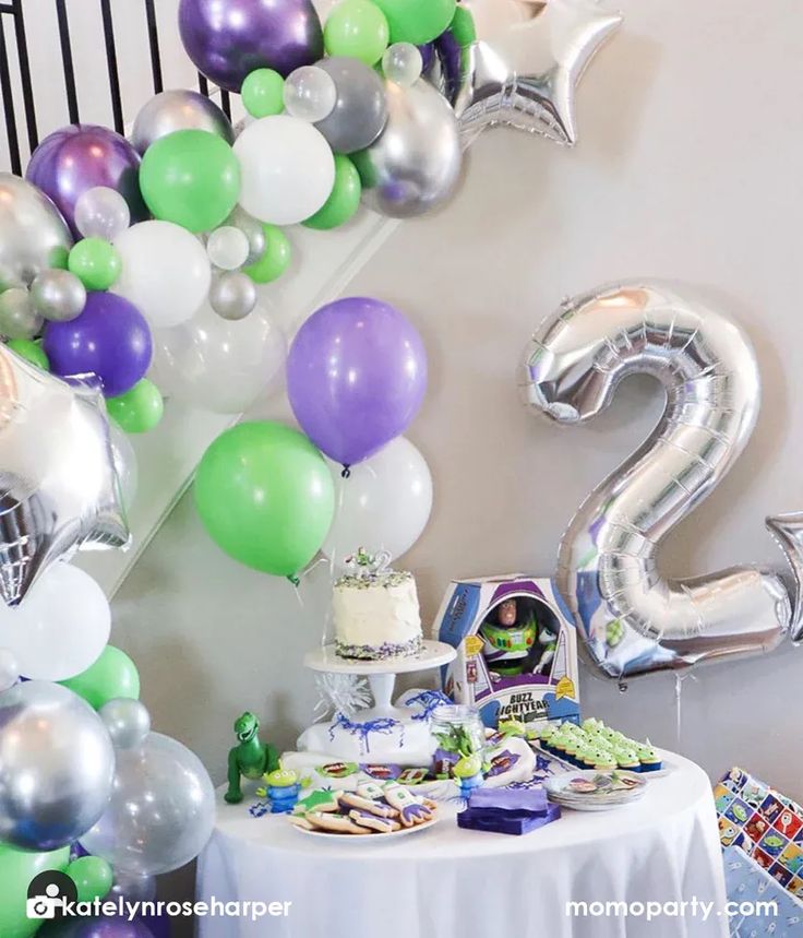 a table topped with balloons and cake next to a stair case filled with other items