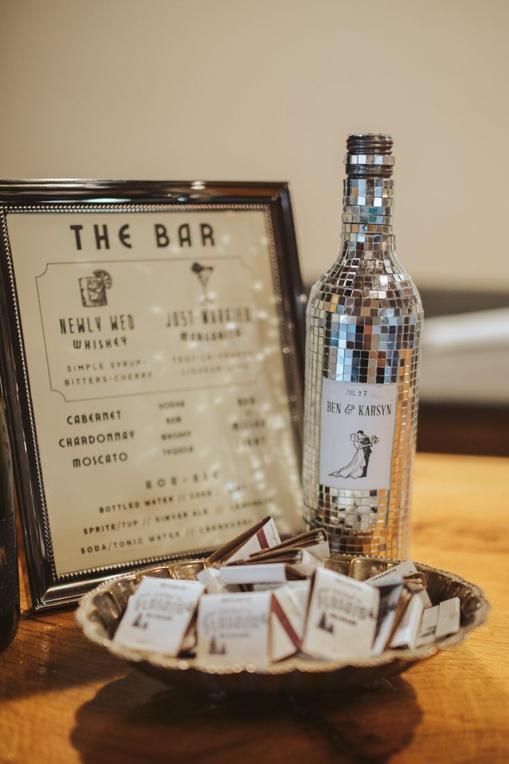 a bottle of liquor sitting on top of a wooden table next to a plate filled with chocolates