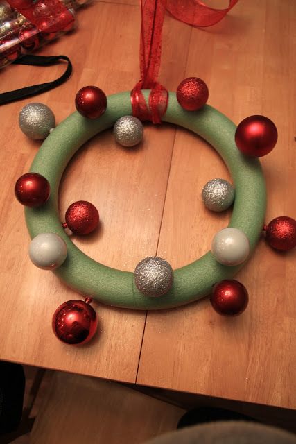 a green wreath with red and white ornaments hanging from it's side on a wooden table