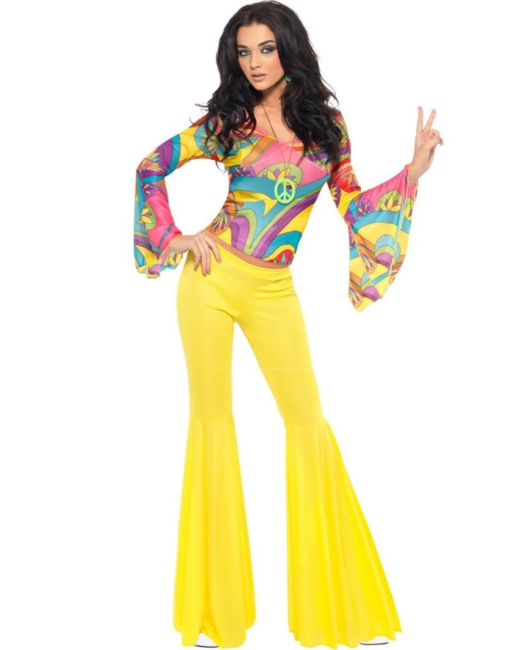 a woman in yellow pants and a colorful top is posing for the camera with her hands up