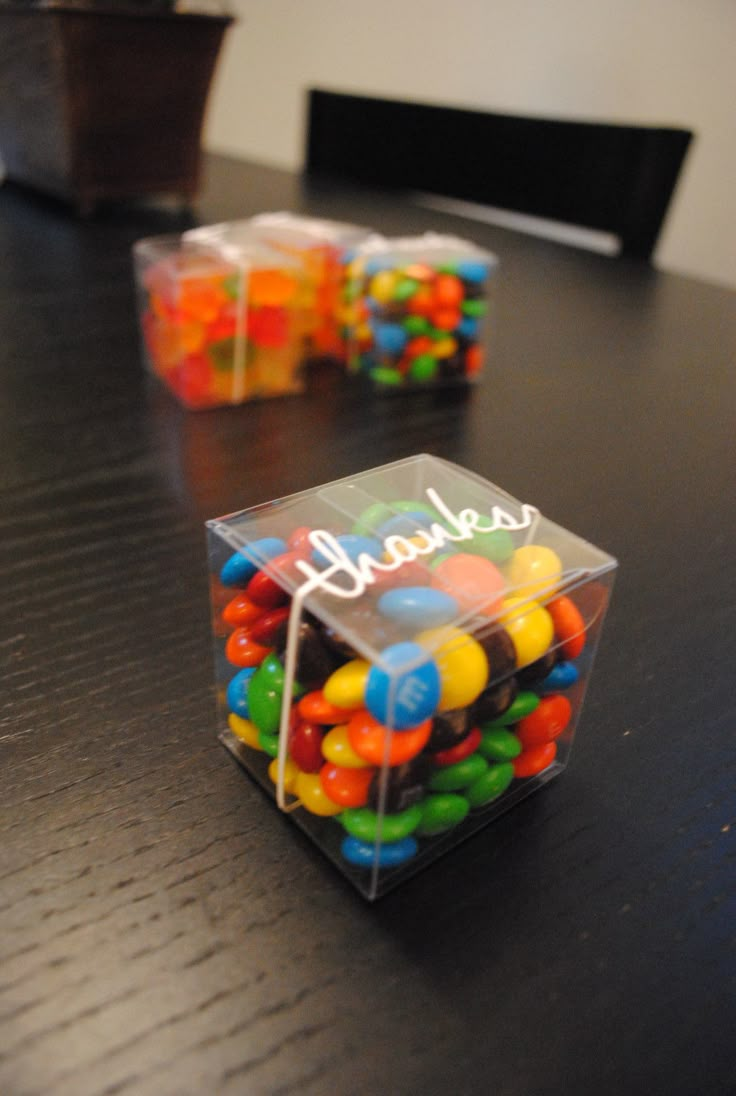 two clear boxes filled with candy sitting on top of a table