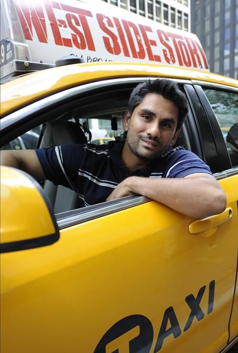 a man sitting in the driver's seat of a taxi cab on a city street