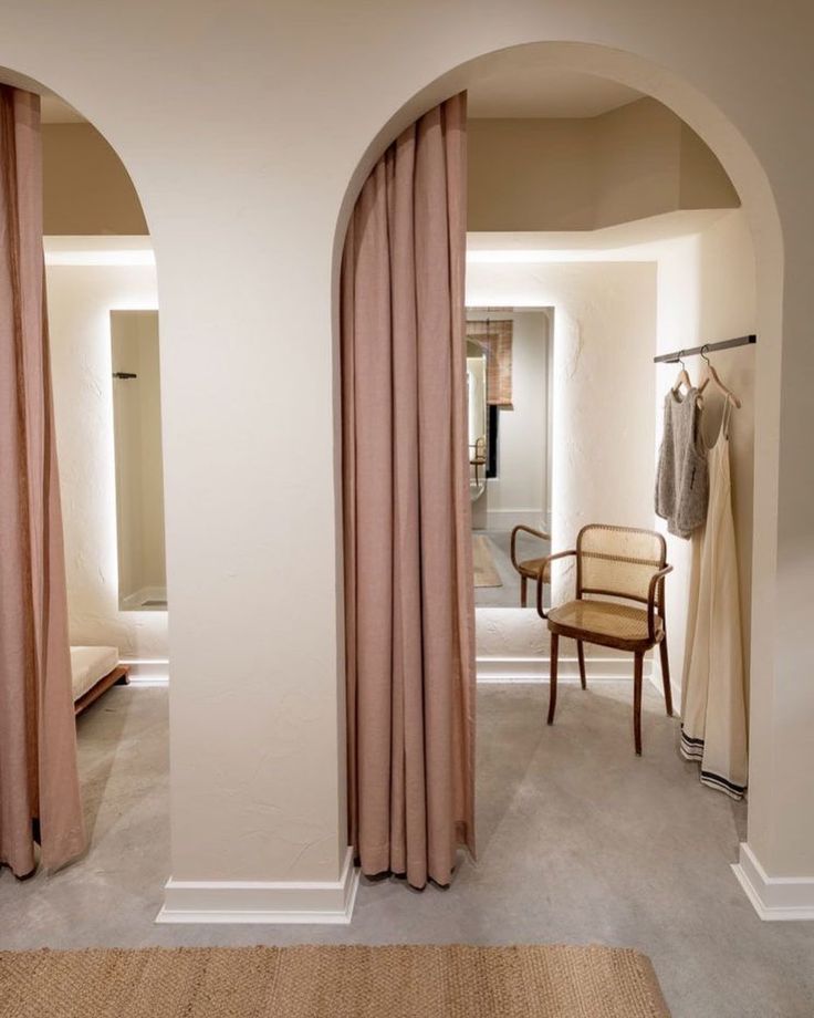 an arched doorway leads into a bedroom with beige curtains