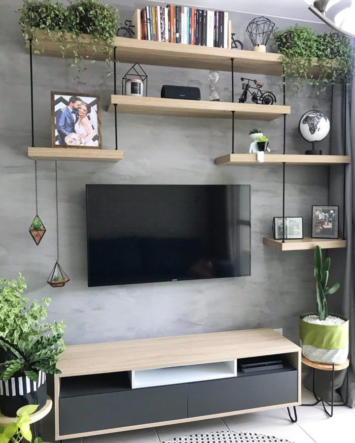 a flat screen tv sitting on top of a wooden shelf next to a potted plant