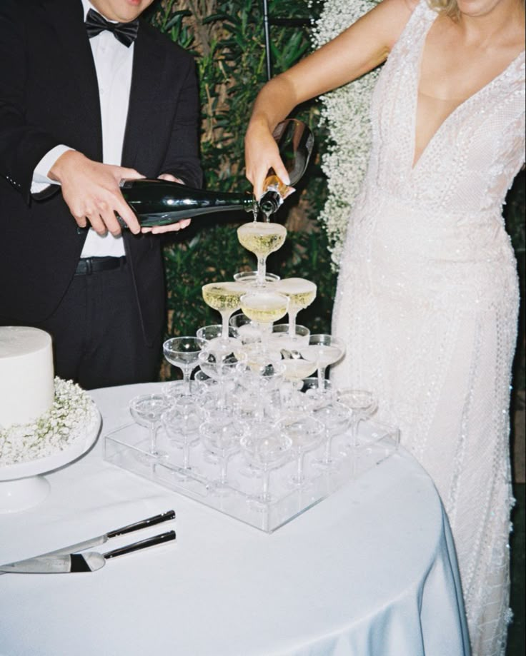 a bride and groom are cutting into their wedding cake with champagne glasses in front of them