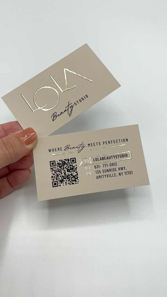 a person is holding two business cards in their hand