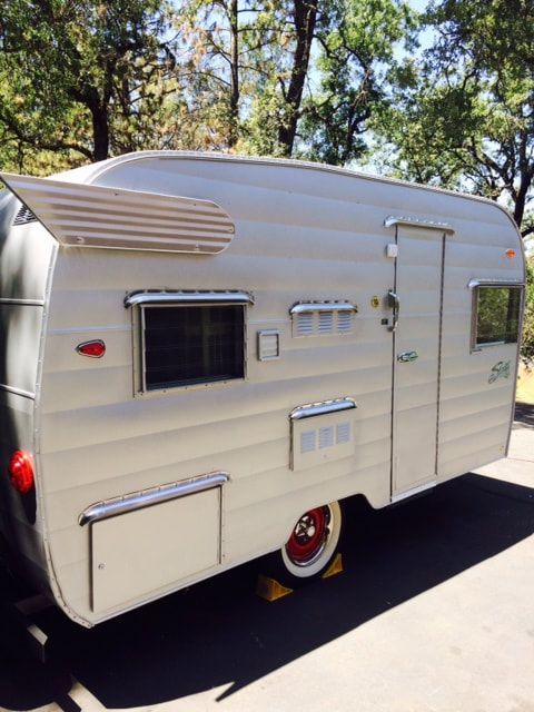 an old camper is parked on the side of the road in front of some trees