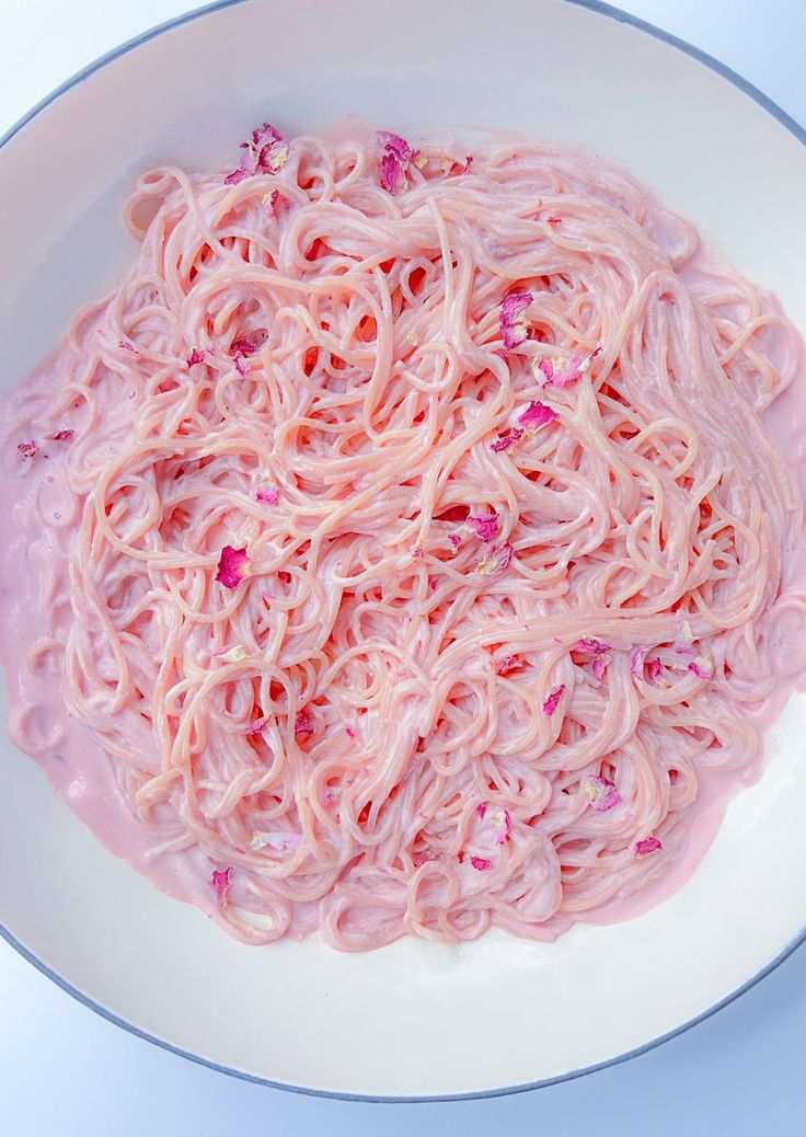 a white bowl filled with pink noodles on top of a table