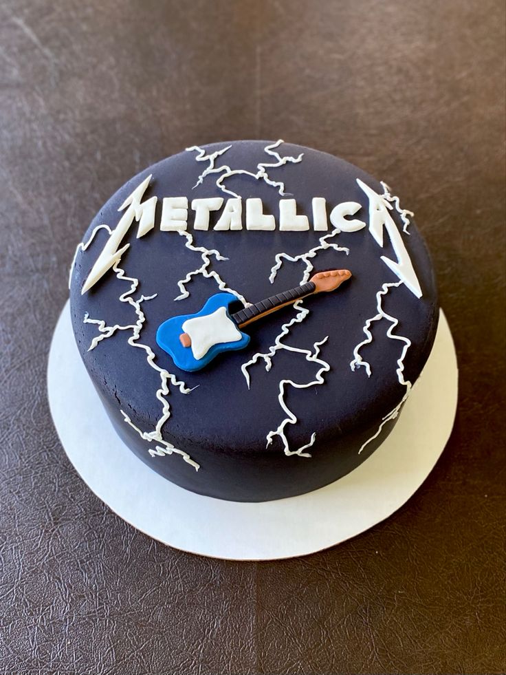 there is a cake with the name metallic on it and a guitar in the middle