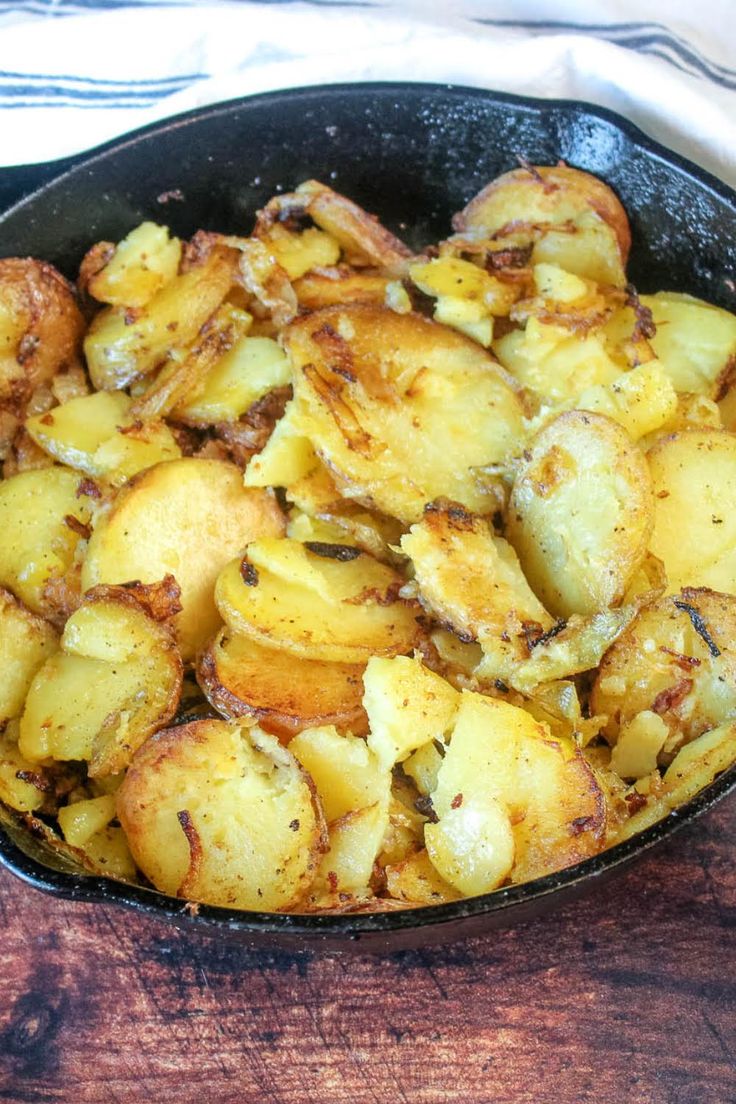 a skillet filled with potatoes on top of a wooden table