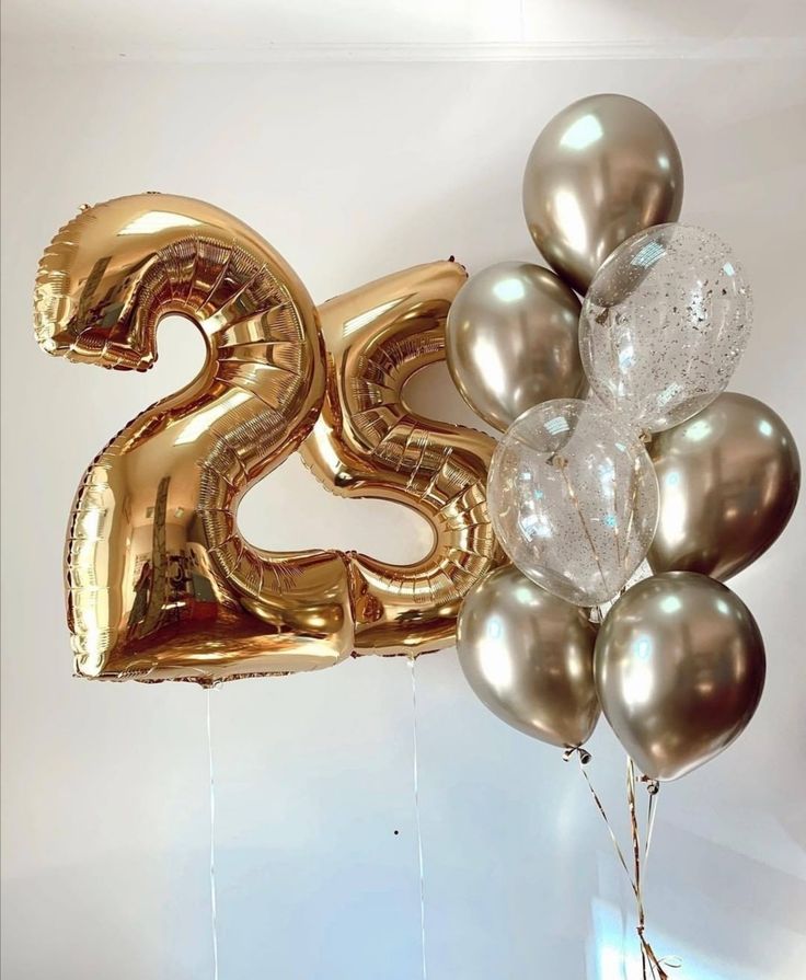 the number twenty five balloons are in gold and silver colors, with one balloon attached to it