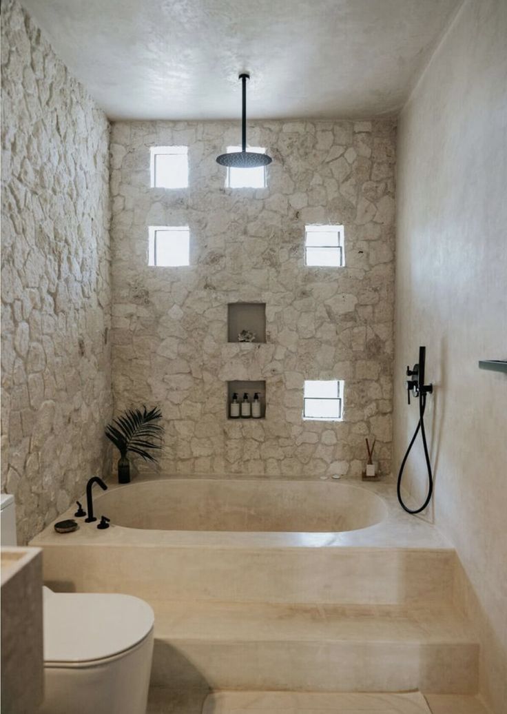 a white bathroom with stone walls and flooring