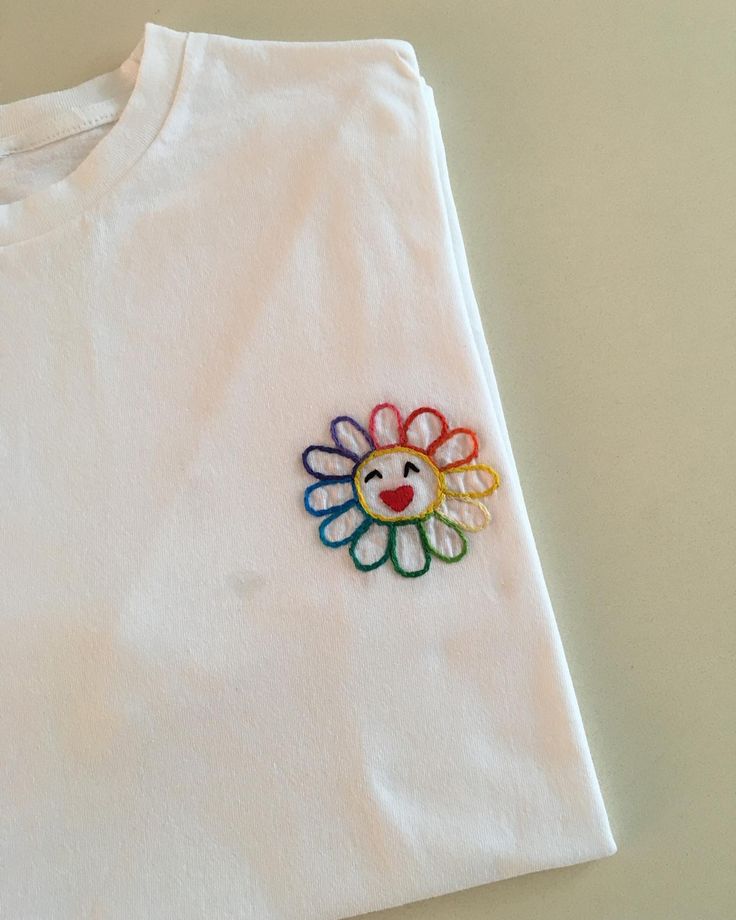 a white t - shirt with a colorful flower embroidered on the front and back side