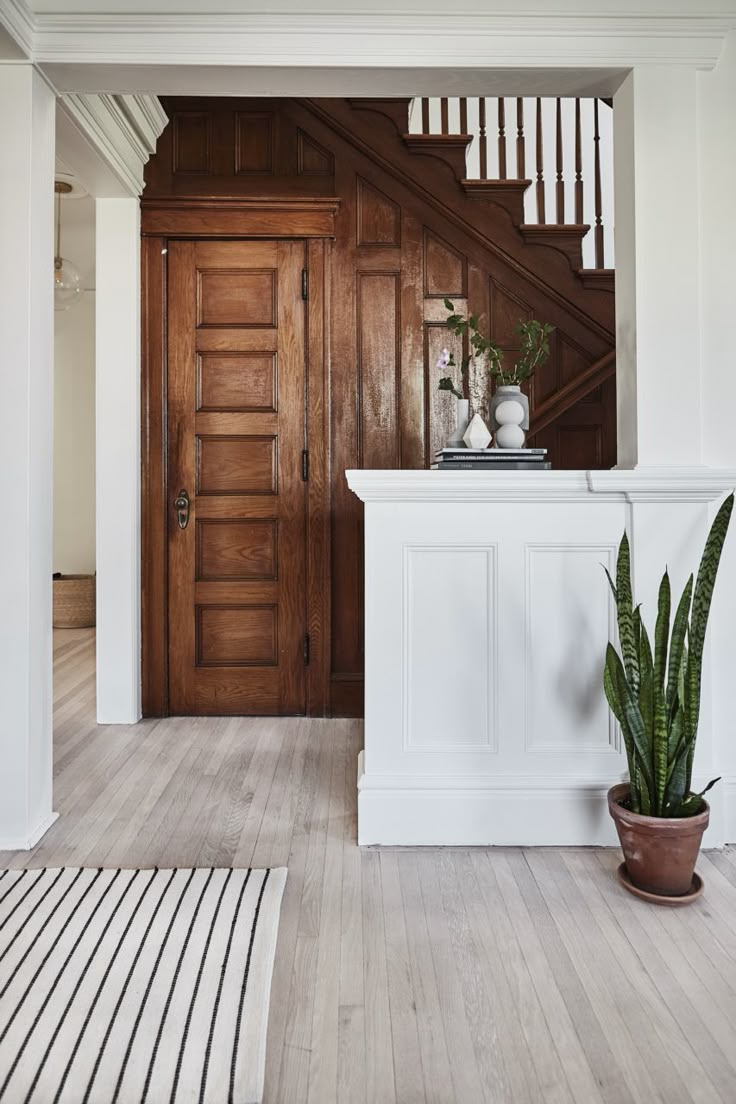 an entryway with wood paneling and white walls, potted plants on the counter