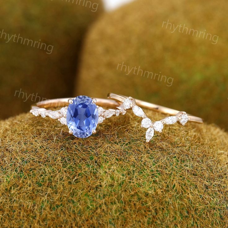 a ring with an oval blue stone surrounded by small white diamonds on top of moss