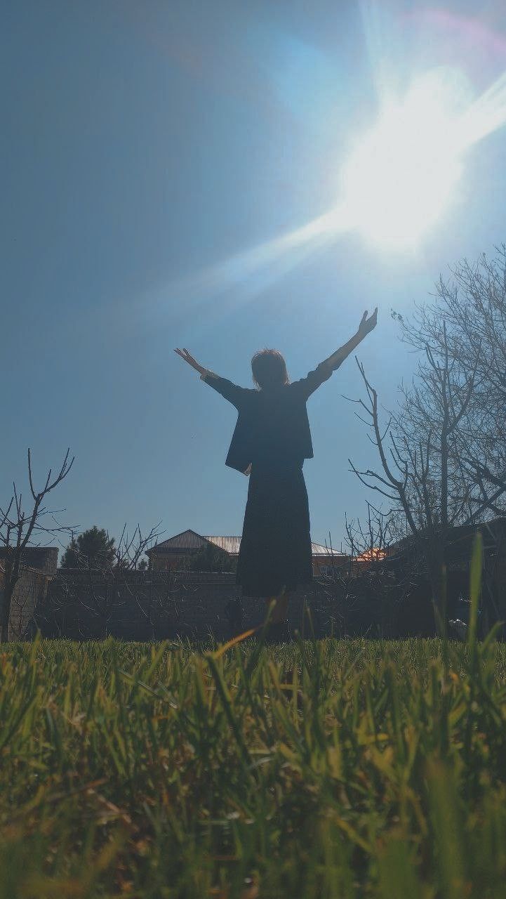 a person standing in the grass with their arms outstretched