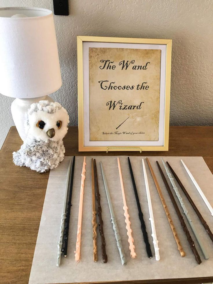 an owl figurine sitting next to a collection of wands on a table