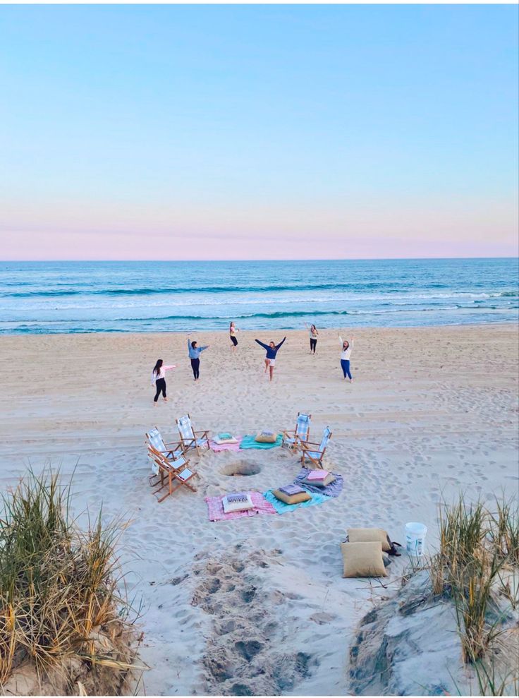 people doing yoga on the beach with their arms in the air