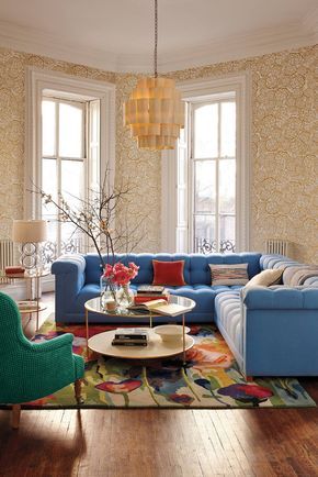 a living room with blue couches and colorful rugs on the wooden flooring