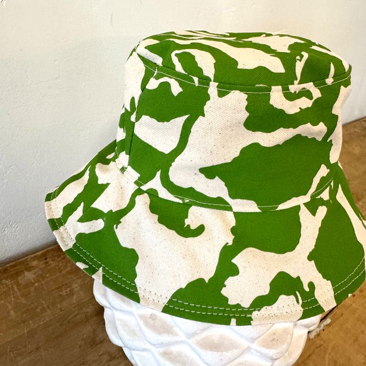 The perfect lightweight bucket hat for sunny spring and summer days! Now available in two sizes (Small/Medium & Large) since we had some issues with these not be consistent last season. Print: 1 color screen print Size: Small/Medium 21-22.5 inches, Large 22.5-23 inches (inside circumference) Material: Cotton, Cotton Canvas Lining Care: Hand Wash Cold. Hang or Lay Flat to Dry. Do not dry in the dryer. Cotton Bucket Hat With Uv Protection For Vacation, Cotton Bucket Hat For Beach Season, One Size, Cotton Bucket Hat For Beach Season, Fun Sun Hat With Short Brim For Spring, Fun Spring Sun Hat With Short Brim, Trendy Green Wide Brim Sun Hat, Fun Summer Bucket Hat With Curved Brim, Adjustable Cotton Bucket Hat For Beach Season, Trendy Cotton Sun Hat For Vacation