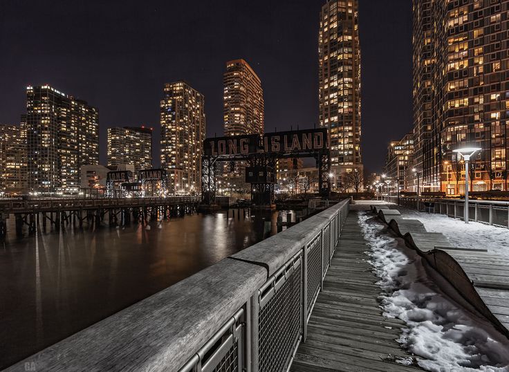 the city skyline is lit up at night, with snow on the ground and buildings in the background