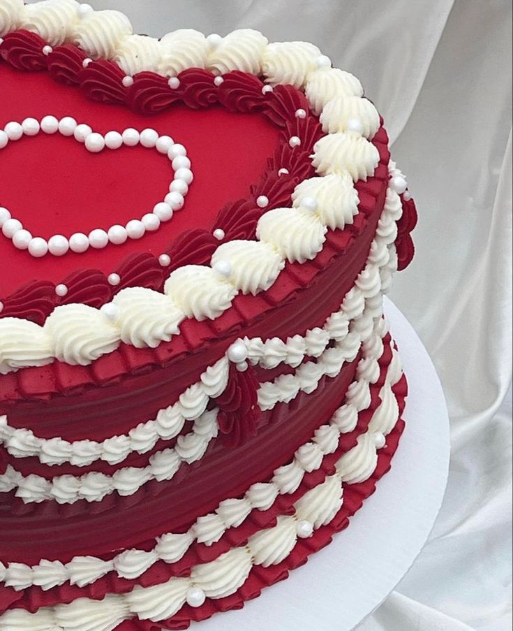 a red and white cake with a heart on top is sitting on a platter