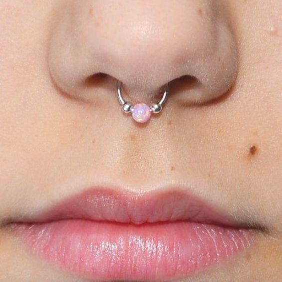 a woman's nose with a pink ope piercing on top of her nose