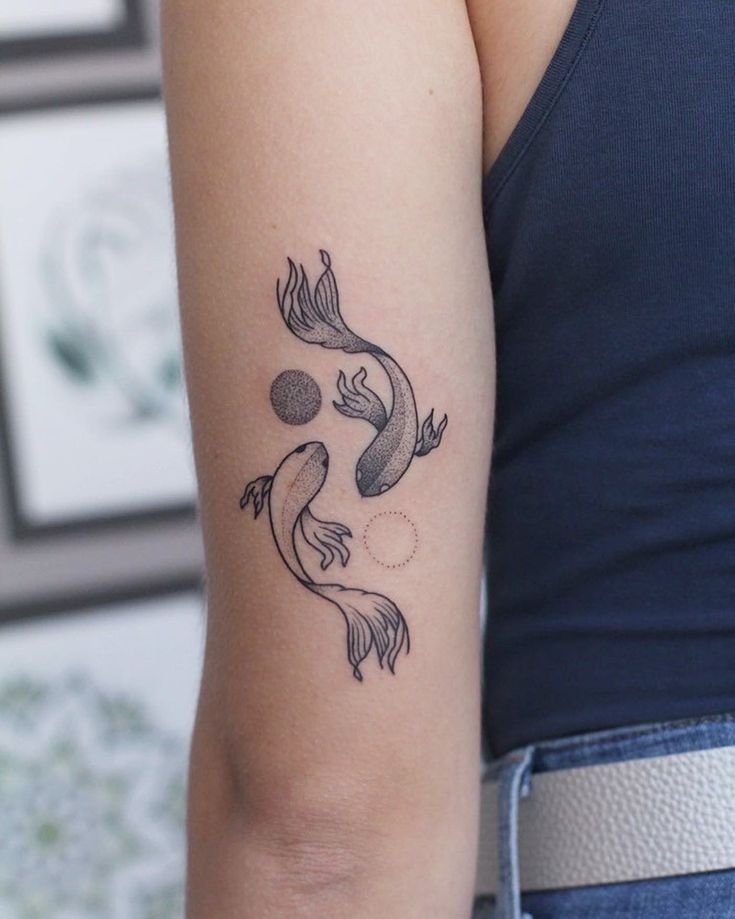 a woman's arm with a fish tattoo on the left side of her arm