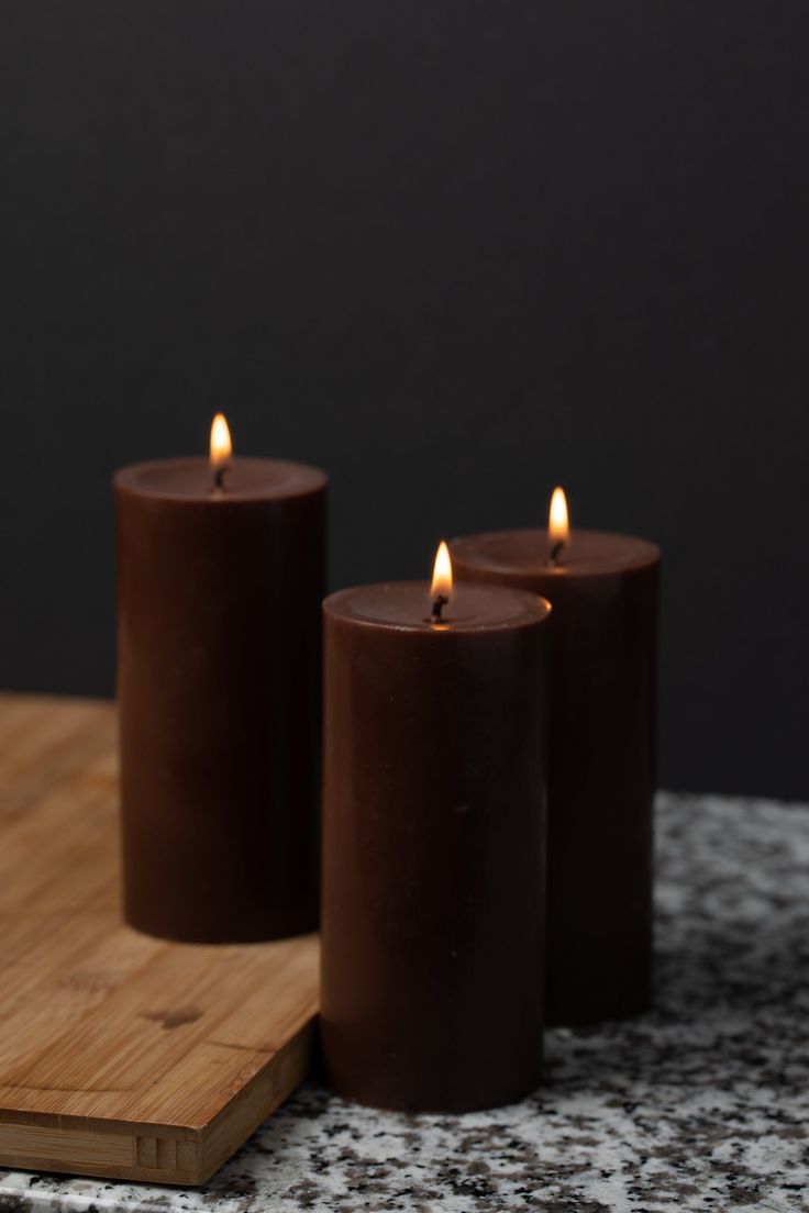 three brown candles sitting on top of a wooden cutting board