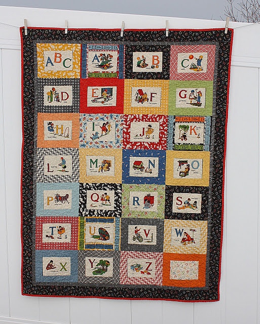 a child's quilt hanging on the side of a fence with letters and numbers