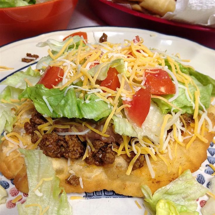 a taco sandwich with lettuce, tomatoes and cheese on it sitting on a plate