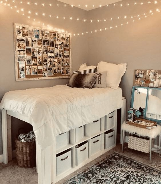 a white bed with lots of drawers underneath it and lights strung above the headboard