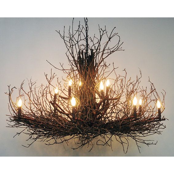 a chandelier made out of branches with lit candles in the center and one light on each side