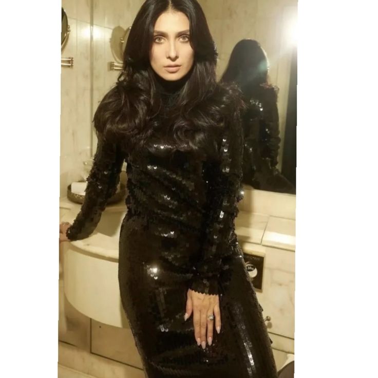 a woman in a shiny black dress posing for the camera