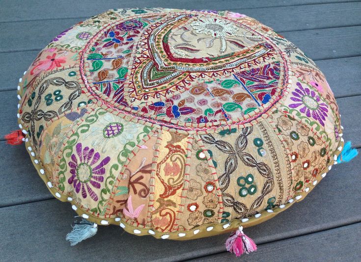 a decorative round pillow with tassels and beads on the outside patio floor,