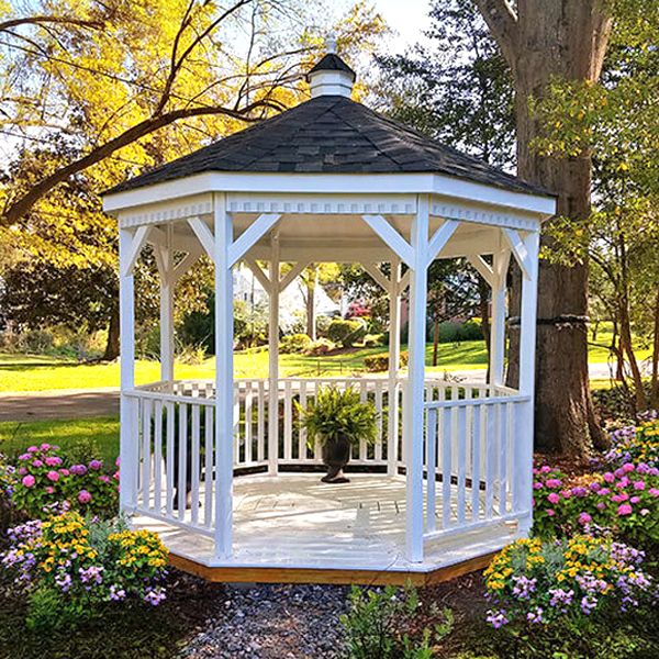 a white gazebo surrounded by flowers and trees