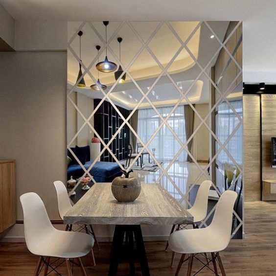 a dining room table with white chairs and a large mirror on the wall behind it