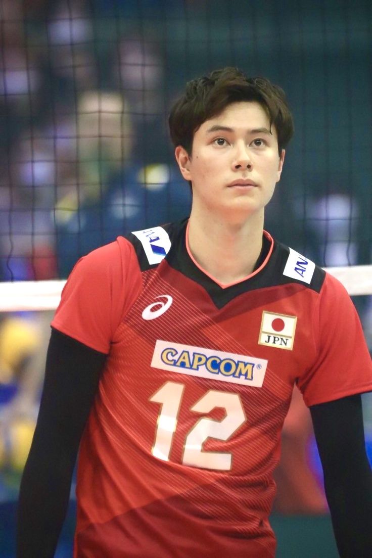 a young man standing in front of a volleyball net