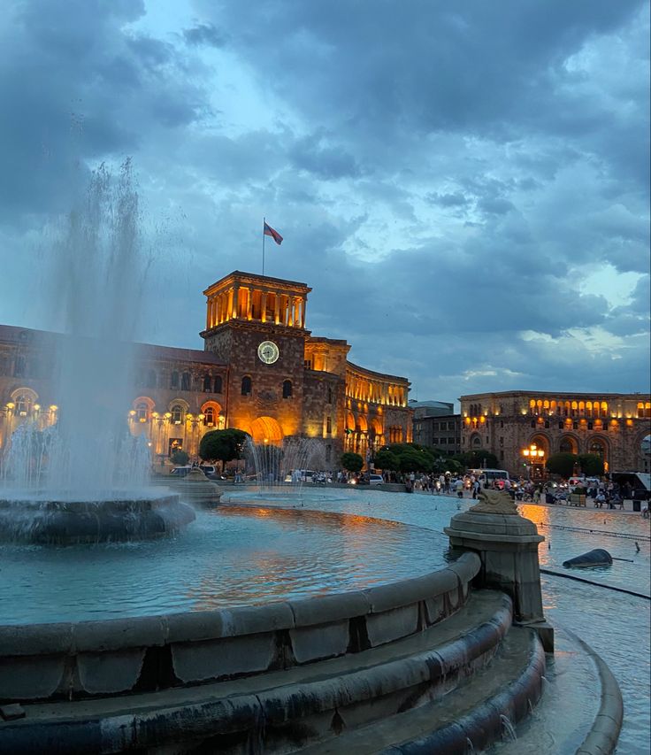 a fountain in front of a building with a clock tower