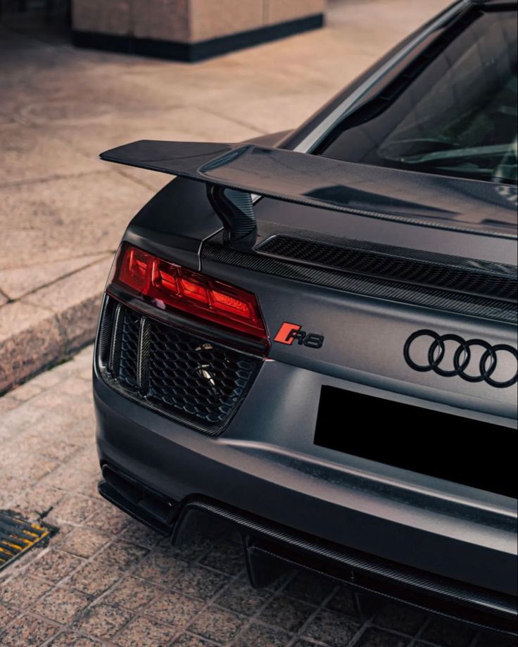 the rear end of an audi car parked in front of a curb on a city street